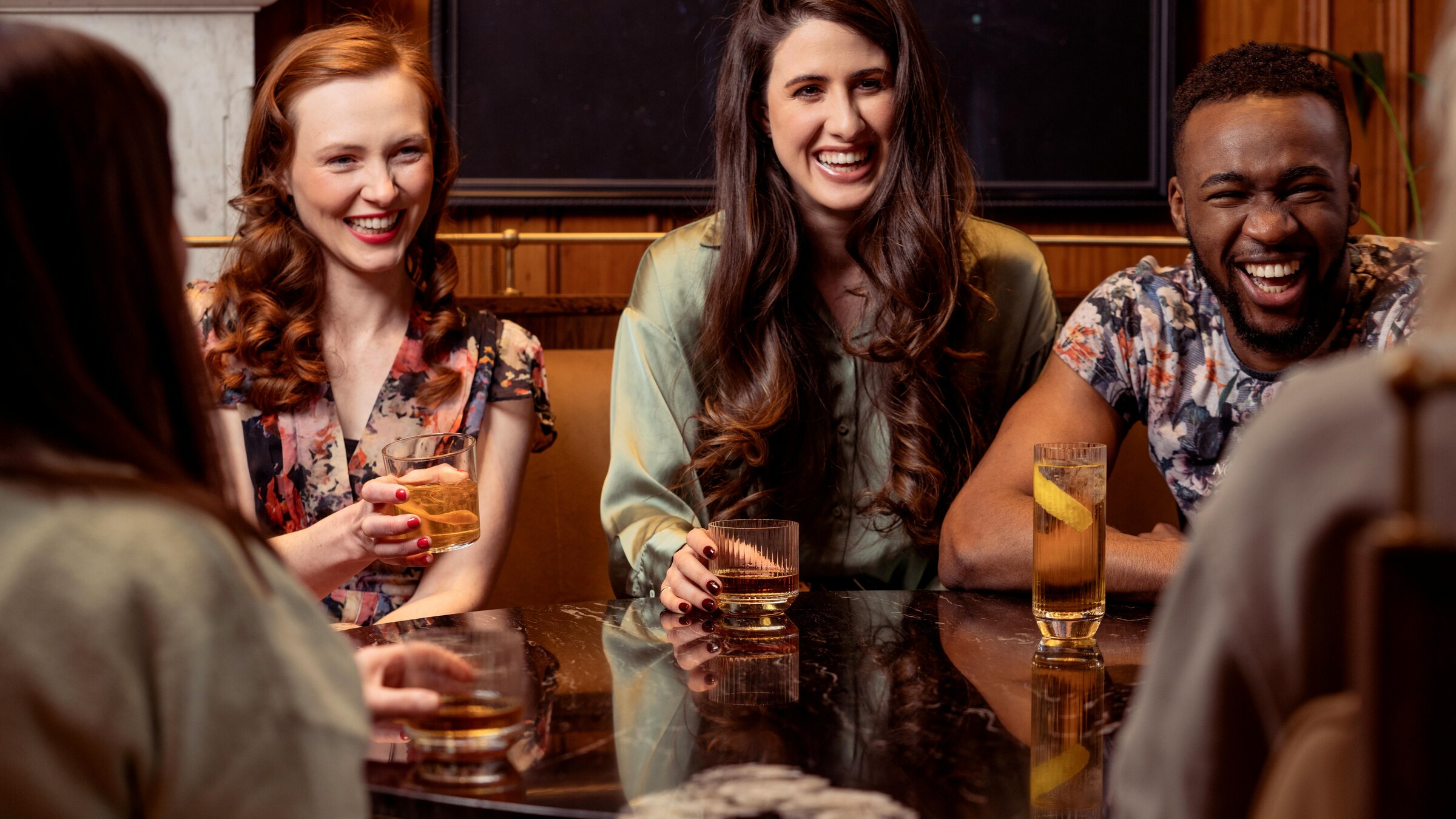 Group of friends smiling with drinks in a low-light bar